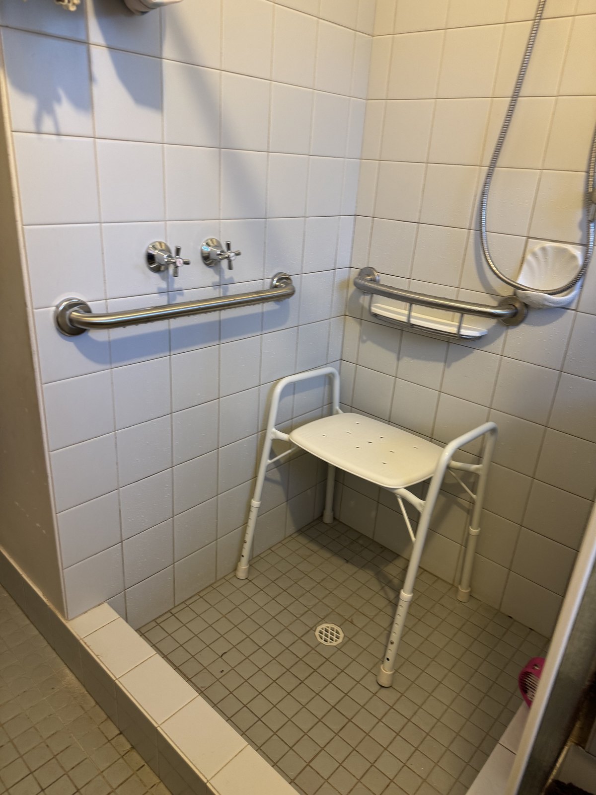 Accessible shower fitted with grab rails and a shower chair